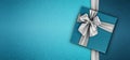 Merry christmas gift card, blue box with shiny silver ribbon bow isolated on turquoise glittering background, top view copy space Royalty Free Stock Photo