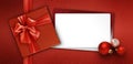 Merry christmas gift card with red box with ribbon bow, white ticket and silver ball isolated on red glitter background, top view Royalty Free Stock Photo