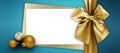 Merry christmas gift card, white ticket with golden shiny ribbon bow and xmas balls top view on glittering turquoise background,