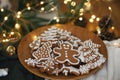Merry Christmas! Gingerbread cookies with icing in plate on wooden rustic table with fir branches, festive decorations and Royalty Free Stock Photo