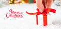 Merry Christmas greeting card with a man hand holding a gift box with red ribbon on the snow and blurred lights on the Royalty Free Stock Photo