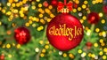 Merry Christmas greetings in Icelandic. Blurred background of beautiful Christmas tree decorated with bright golden lights, toys,