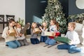 Merry Christmas. Group of children sitting in cozy room after exchanging Xmas presents at fun party Royalty Free Stock Photo