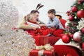 Merry christmas, happy family at home, parents giving the gift to their child near the illuminated and decorated tree, joyful and