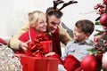 Merry christmas, happy family at home, parents giving the gift to their child near the illuminated and decorated tree, joyful and