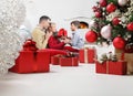 Merry christmas, happy family stay at home, parents giving the gift to their child near the illuminated and decorated tree, joyful