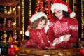 Merry Christmas and Happy Holidays. Cheerful cute curly little girl and her older sister in santas hats cooking Royalty Free Stock Photo