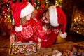 Merry Christmas and Happy Holidays. Cheerful cute curly little girl and her older sister in santas hats cooking Royalty Free Stock Photo