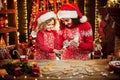 Merry Christmas and Happy Holidays. Cheerful cute curly little girl and her older sister in santas hats cooking Royalty Free Stock Photo
