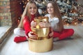 Merry Christmas and Happy Holidays. Cheerful cute kid girls opening gifts. Children near the tree in the morning. Royalty Free Stock Photo