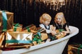 Merry Christmas and Happy Holidays! Cheerful girl and boy in a bath with Christmas gifts in gold wrappers. Royalty Free Stock Photo