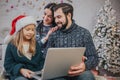 Merry Christmas and Happy Holidays Cheerful mom, dad and her cute daughter girl to use a laptop. Parent and little child Royalty Free Stock Photo