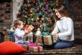 Merry Christmas and Happy Holidays! Cheerful mom and her cute daughter exchanging gifts. Parent and little child having fun near C Royalty Free Stock Photo