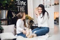 Merry Christmas and Happy Holidays. Cheerful mom and her cute daughter girl opening a Christmas present. Parent and Royalty Free Stock Photo