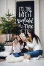 Merry Christmas and Happy Holidays. Cheerful mom and her cute daughter girl opening a Christmas present. Parent and Royalty Free Stock Photo