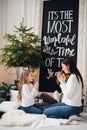 Merry Christmas and Happy Holidays. Cheerful mom and her cute daughter girl opening a Christmas present. Parent and Royalty Free Stock Photo