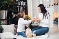 Merry Christmas and Happy Holidays. Cheerful mom and her cute daughter girl opening a Christmas present. Parent and Royalty Free Stock Photo