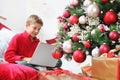 Merry christmas and happy holidays, child stay at home with computer near the illuminated and decorated tree and wrapped gift