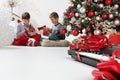 Merry christmas and happy holidays, children look at the gift packages near the christmas tree with musical instruments, at home Royalty Free Stock Photo