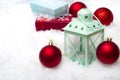 Merry Christmas and Happy Holidays concept with red baubles, gift boxes and a green lantern on snow with copy space Royalty Free Stock Photo