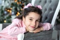 Merry Christmas, happy holidays! Cute girl with bows on head sitting on sofa against Christmas tree. child is waiting for New Year Royalty Free Stock Photo