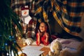 Merry Christmas and Happy Holidays. Cute little child girl writes the letter to Santa Claus near Christmas tree Royalty Free Stock Photo