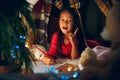 Merry Christmas and Happy Holidays. Cute little child girl writes the letter to Santa Claus near Christmas tree Royalty Free Stock Photo