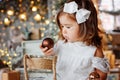 Merry Christmas and Happy Holidays. A cute little girl is decorating a Christmas tree indoors. Happy little smiling girl with Royalty Free Stock Photo
