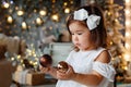 Merry Christmas and Happy Holidays. A cute little girl is decorating a Christmas tree indoors. Happy little smiling girl with