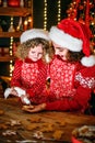 Merry Christmas and Happy Holidays. Cheerful cute curly little girl and her older sister in santas hats cooking Royalty Free Stock Photo