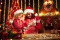 Merry Christmas and Happy Holidays. Cheerful cute curly little girl and her older sister in santas hats cooking Royalty Free Stock Photo