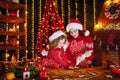 Merry Christmas and Happy Holidays. Cheerful cute curly little girl and her older sister in santas hats cooking Royalty Free Stock Photo