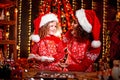 Merry Christmas and Happy Holidays. Cheerful cute curly little girl and her older sister in santas hats cooking Royalty Free Stock Photo