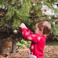 Merry Christmas and Happy Holidays. Father in red Christmas hat and daughter in red sweater decorating the Christmas tree outdoor