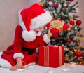 Merry Christmas and happy holidays. Funny cute girl in surprise and delight opens the gift near a tree