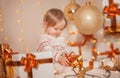 Merry Christmas and Happy Holidays! Little cute kid girl sitting in decorated room holding present box with surprise and smiling. Royalty Free Stock Photo