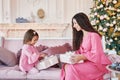Merry Christmas and happy holidays! Merry mom and her cute daughter. girls exchange gifts. Parent and little child having fun near Royalty Free Stock Photo
