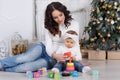 Mom with a little daughter playing on Christmas Eve on the background of a beautiful Christmas tree Royalty Free Stock Photo