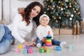 Mom with a little daughter playing on Christmas Eve on the background of a beautiful Christmas tree Royalty Free Stock Photo