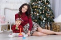 Mom with a little daughter playing on Christmas Eve on the background of a beautiful Christmas tree Royalty Free Stock Photo