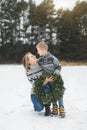 Merry Christmas and Happy Holidays. Mother and her little son walking together in winter forest and holding Christmas Royalty Free Stock Photo