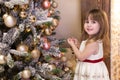 Merry Christmas and happy holidays! New Year 2020. Portrait of a cute little girl decorates a Christmas tree in the living room wi Royalty Free Stock Photo