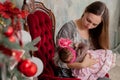 Merry Christmas and Happy Holidays Pretty young mom reading a book to her cute daughter near Christmas tree indoors Royalty Free Stock Photo