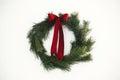 Merry Christmas and Happy Holidays! Stylish christmas wreath with red bow hanging on white wall. Simple traditional xmas wreath Royalty Free Stock Photo