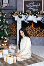 Merry Christmas, happy holidays! Woman in white sweater, warm and cozy evening in New Year interior design, a tree, gifts, a firep Royalty Free Stock Photo