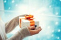 Merry Christmas and Happy New Year! Close up female hands holding present box indoor while staying infront of window on snowflakes Royalty Free Stock Photo