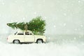 Merry Christmas Happy New Year concept. Retro toy car with christmas tree on snowy winter background. Copy space for your text Royalty Free Stock Photo