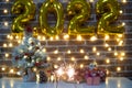 Merry Christmas and happy new year, defocused small Christmas tree on table with christmas presents and 2022 in golden inflatable