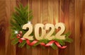 Merry Christmas and Happy New Year 2022. Golden 3D numbers with red ribbons, branch of christmas tree