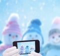 Three happy snowmen making selfie on smartphone.